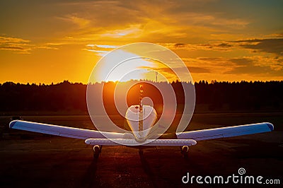 Rear view of a parked small plane on a sunset background. Silhouette of a private airplane landed at dusk. Stock Photo