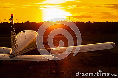 Rear view of a parked small plane on a sunset background. Silhouette of a private airplane landed at dusk. Stock Photo