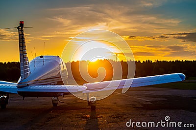 Rear view of a parked small plane on a sunset background. Silhouette of a private airplane landed at dusk. Stock Photo