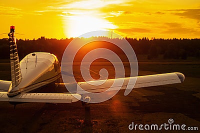 Rear view of a parked small plane on a sunset background. Silhouette of a private airplane landed at dusk. Stock Photo