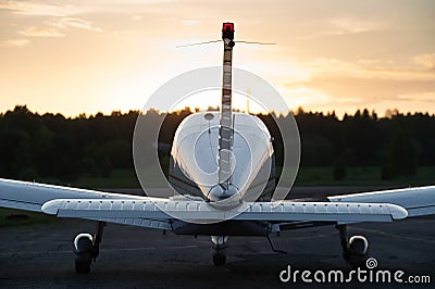 Rear view of a parked small plane on a sunset background. Silhouette of a private airplane landed at dusk. Stock Photo