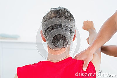 Rear view of a physiotherapist massaging mature mans arm Stock Photo