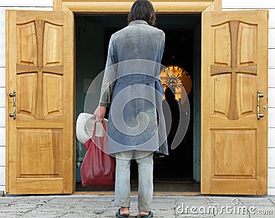 Rear view of a poor man standing in front of open church doors Editorial Stock Photo