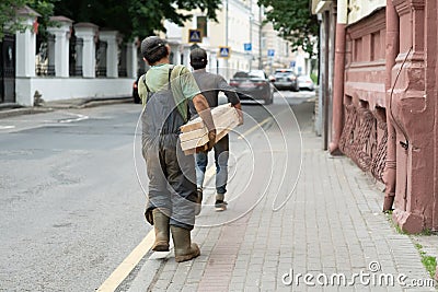 Rear view portrait of mature workman carrying long wooden board moving material in factory workshop Editorial Stock Photo