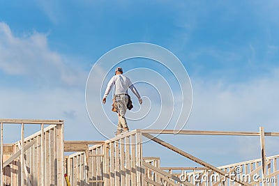 Rear view roofer builder worker on wooden roof trusses construct Stock Photo