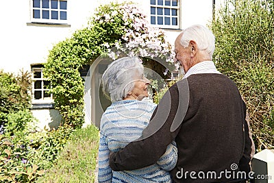 Rear View Of Senior Couple Outside Pretty Cottage Stock Photo