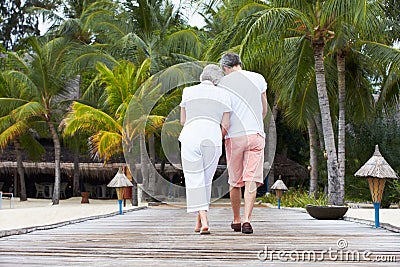Rear View Of Senior Couple Walking On Wooden Jetty Stock Photo