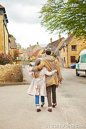 Rear view of a silhouette of a loving couple, hugging while visiting a destination city, walking along the old street of English Stock Photo