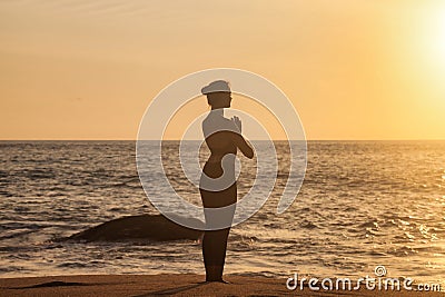 Rear view silhouette slim woman does yoga on tropical sea coast or ocean beach outdoors at sunset Stock Photo