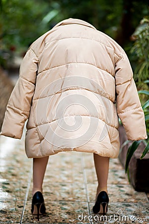 Rear view on small woman dwarf dressed in beige jacket Stock Photo