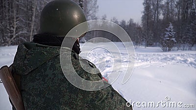 Rear view of the soldier in the forest in winter. Clip. The soldier stands at his post guarding him. Military protection Editorial Stock Photo