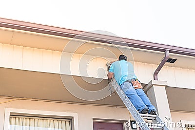 Rear view of technician installing surveillance camera on roof Editorial Stock Photo