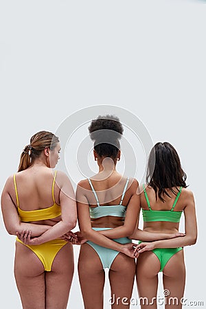 Rear view of three female models with different body types in colorful underwear holding hands, supporting each other Editorial Stock Photo