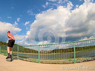 Rear view to inline skater in red t-shirt and black pants skating on the bridge . Outdoor inline skating Stock Photo