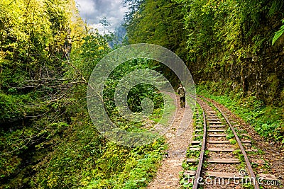 Rear view of tourist in camouflage enjoying amazing beauty of nature. Excursion on old narrow railroad in mountain region Editorial Stock Photo