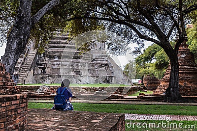 Rear view of Tourist woman is sitting alone sit rest at Wat Ratchaburana Editorial Stock Photo