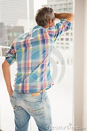 Rear view of troubled casual businessman leaning against window Stock Photo