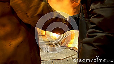 Rear view of two steelmakers at ingot casting shaking hands in front of electric arc furnace in hot shop, metallurgical Stock Photo