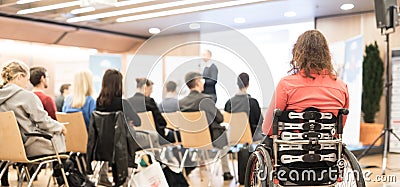 Rear view of unrecognizable woman on a wheelchair participating at business conference talk. Editorial Stock Photo