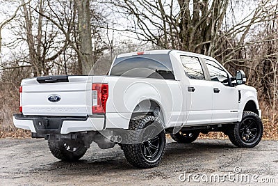 Rear view of a white 2020 Ford F-250 pickup truck with lifted wheels on a dirt road Editorial Stock Photo