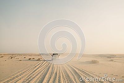 Rear view of white Jeep driving through white sandy desert during sunset Editorial Stock Photo