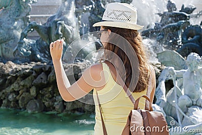 Rear view woman throwing coin into fountain Stock Photo