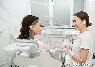 Visit to dentist hygienist. Rear view of a woman in dentists chair during regular dental appointment in white contemporary Stock Photo