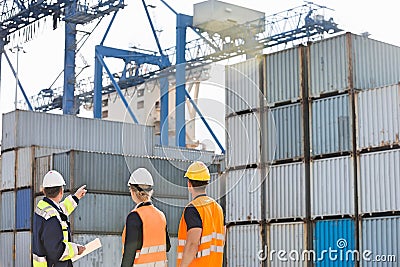 Rear view of workers inspecting cargo containers in shipping yard Stock Photo