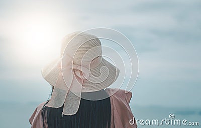 Rear view young Asian woman standing of happy attractive with hands holding sun hat up, sunny day, summer sea, blue sky background Stock Photo