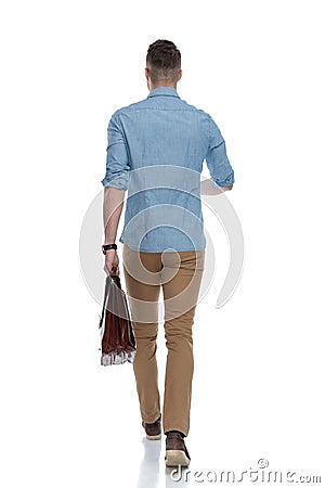 Rear view of young casual holding briefcase, walking Stock Photo