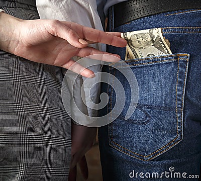 Rear View Of young couple holding hands, second hand wife pulls money from the pocket of her husband`s Stock Photo