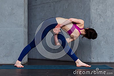 Rear view of young female yogi in sports bra and leggings doing bound extended side angle pose, baddha utthita Stock Photo