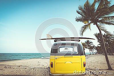 Rear of vintage car parked on the tropical beach seaside with a surfboard on the roof Stock Photo