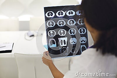 Rearview of ethnic female doctor analyzing X-ray or MRI scan while working in hospital, selective focus. Physician looking at CT Stock Photo