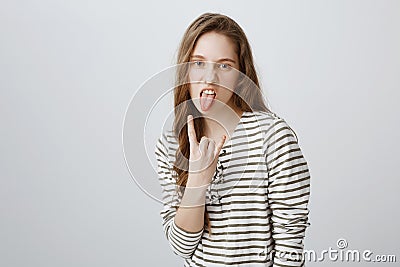 Rebel teenager stand against rules and control. Portrait of cool and confident girl with fair hair sticking out tongue Stock Photo