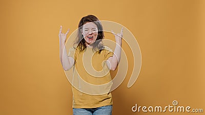 Rebel woman with positive attitude doing rock and roll hand gesture with tongue out wanting to party Stock Photo