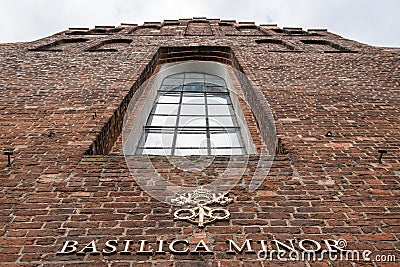 The Basilica Minor sign on the red bricks wall at the entrance to the church Editorial Stock Photo