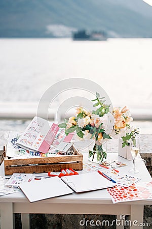 Reception table with a journal of wishes, a set of pencils, markers, beautiful stickers and a bouquet of flowers Stock Photo