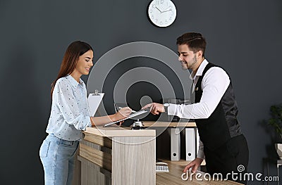 Receptionist registering client at desk Stock Photo