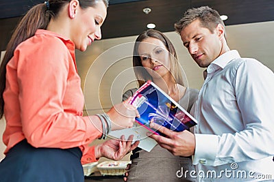 Receptionist showing brochure to business couple in hotel Stock Photo