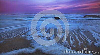 Recessing tide and moonrise over sandy ocean beach Stock Photo