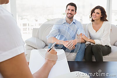 Reconciled couple smiling and talking with their therapist Stock Photo