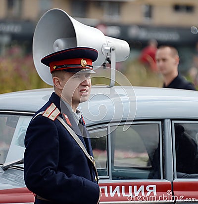 A reconstructor in the Soviet uniform of a police officer at the Moskvich-401 car at an exhibition of old transport. Editorial Stock Photo