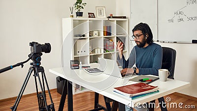 Recording video tutorial about HTML. Professional male computer programming teacher looking at camera and talking while Stock Photo