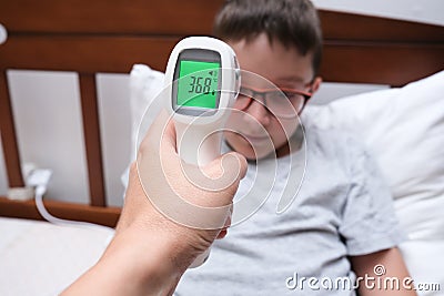 A recovering boy with normal temperature that is shown on a display of infrared contactless thermometer, concept pf Stock Photo