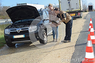 Recovery man with lady broken down by road Stock Photo