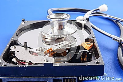 RECOVERY AND REPAIR TECHNOLOGY CONCEPT: Hard Disk Drive HDD with stethoscope isolated on a blue background. Stock Photo