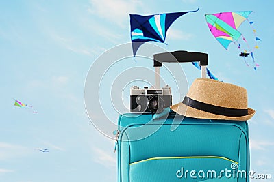 Recreation image of traveler luggage, camera and fedora hat infront of blue sty with flying colorful kites background. holiday and Stock Photo