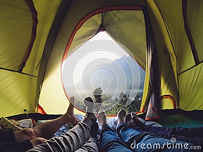Recreation at mountain in camping tent.group of feet lying down inside tent with mountain view in sunset with friend Stock Photo
