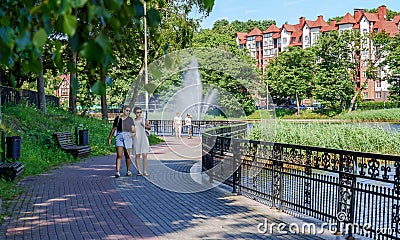 The recreational area along the lake. Fountain on the lake and walking people Editorial Stock Photo